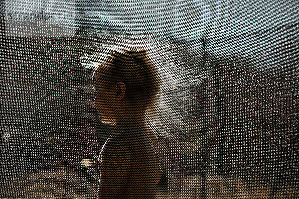 Kind mit statischen Haaren auf Trampolin im Gegenlicht