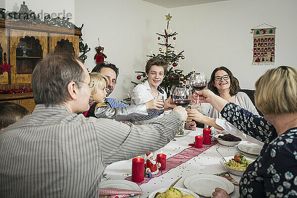Familie klirrt während der Weihnachtsfeier zu Hause mit Weingläsern
