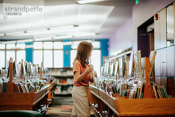 Tween schaut sich Bücher in einer Bibliothek an