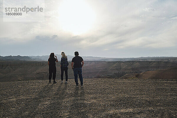 Drei Personen blicken von einem Aussichtspunkt auf den Grand Canyon  windig