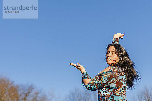 Leidenschaftliches Porträt einer Frau  die vor blauem Himmel tanzt
