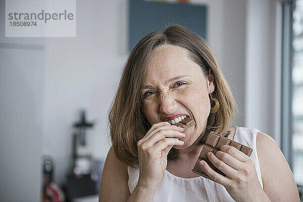 Porträt einer schwangeren Frau  die in der Küche Schokolade isst  München  Bayern  Deutschland