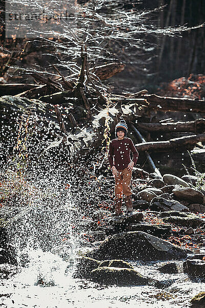 Person beobachtet  wie Wasser im Gebirgsbach hochspritzt