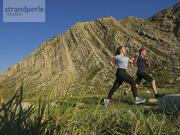 Mann und Frau laufen auf einem Singletrail auf der Klippe von Getxo