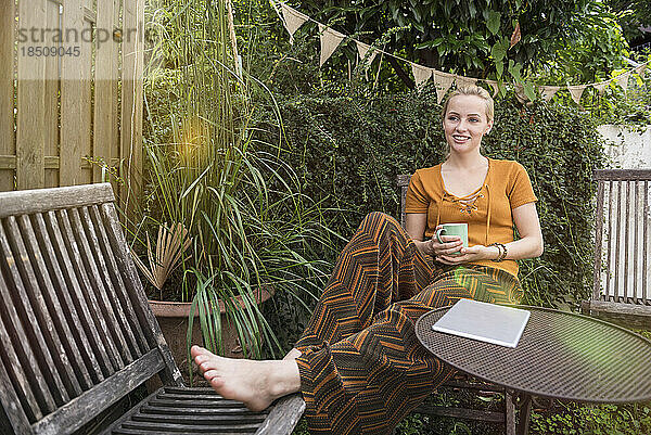 Schöne junge Frau bei einer Tasse Tee im heimischen Garten  München  Bayern  Deutschland