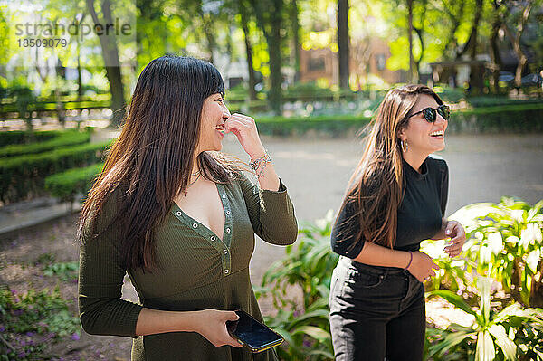 Zwei junge lateinamerikanische Freundinnen gehen im Wald spazieren