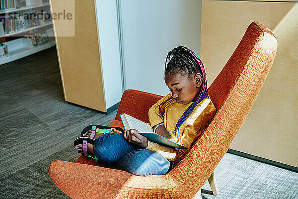 Young girl reading in quiet corner alone