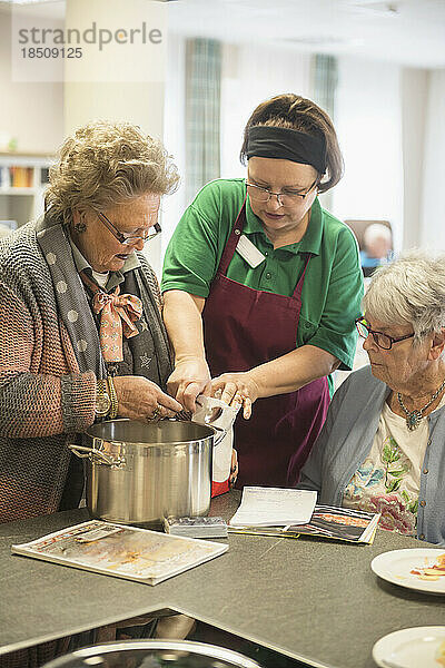 Krankenschwester mit älteren Frauen  die im Altenheim Essen zubereiten