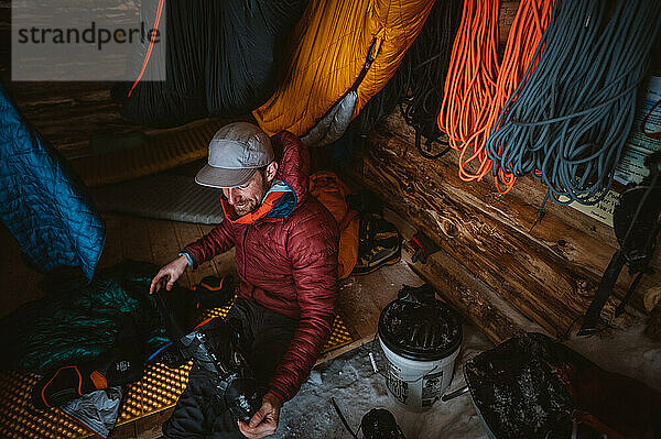 Mann nimmt Liner aus Skischuh in Backcountry-Hütte