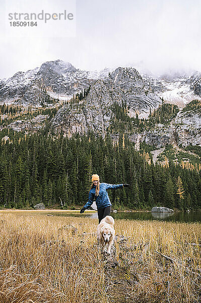 Mädchen mit ihrem Hund beim Wandern in den Bergen mit herbstlichen Lärchen