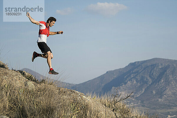 Athletischer Mann springt beim Trailrunning mit einem Mann an einem verlassenen Ort in El Arenal  Hidalgo  Mexiko  über Berge.