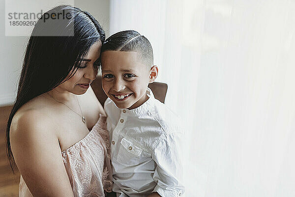 Seitenansicht einer Mutter  die ihren Sohn umarmt  während er in die Kamera lächelt