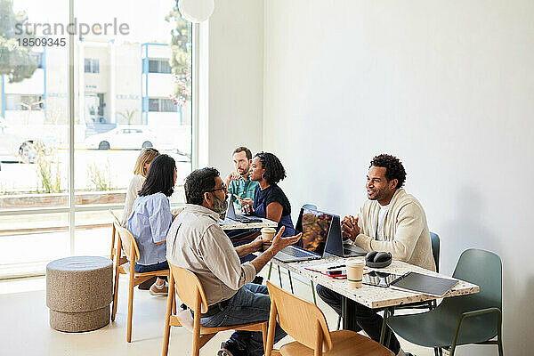 Gemischtrassige Kollegen diskutieren  während sie im Café sitzen