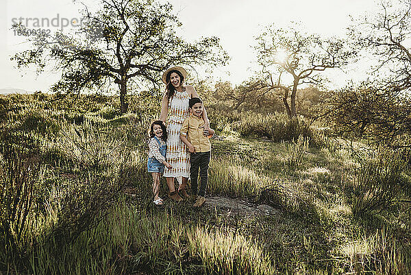 Porträt einer schönen Mutter und kleiner Kinder auf einem sonnigen Feld