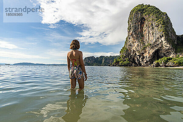 Reisende Frau im türkisfarbenen Wasser mit Blick auf die Phra-Nang-Höhle.