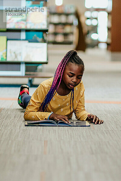 Junges Mädchen liest allein in der Bibliothek