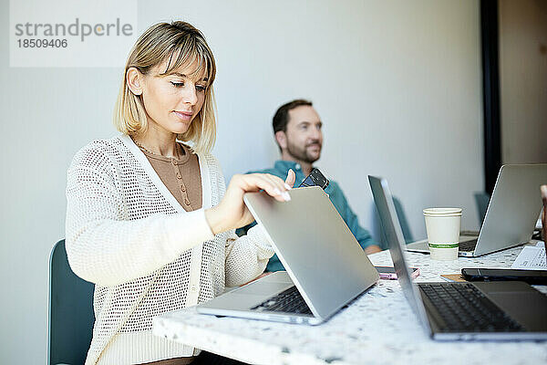 Geschäftsfrau öffnet Laptop am Tisch und sitzt im Café