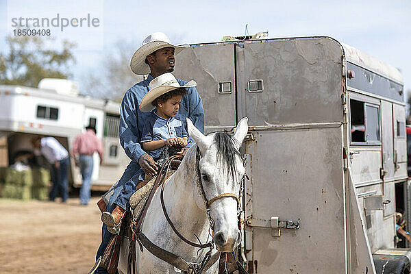 Ein Vater und ein Sohn auf einem Pferd beim Arizona Black Rodeo