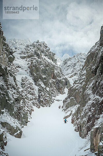 Skifahrer erklimmen beim Backcountry-Skifahren eine verschneite Schlucht