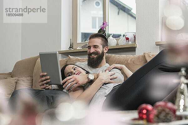Ein Paar schaut sich ein digitales Tablet an und entspannt sich auf dem Sofa