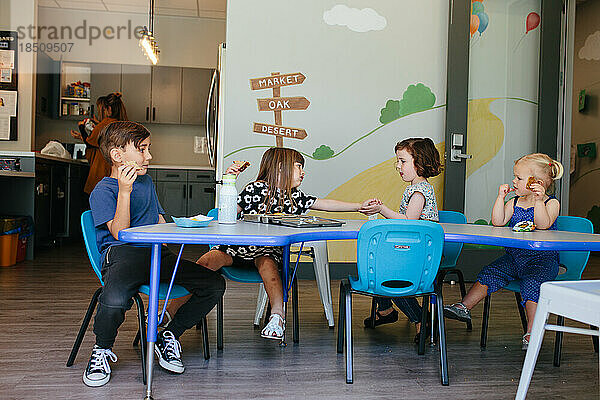 Kinder sitzen zum Mittagessen in einer Bildungseinrichtung
