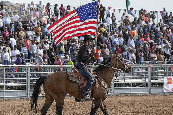 Ein Reiter trägt eine amerikanische Flagge und eröffnet das schwarze Rodeo in Arizona