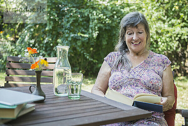 Ältere Frau liest ein Buch im Garten  Altötting  Bayern  Deutschland