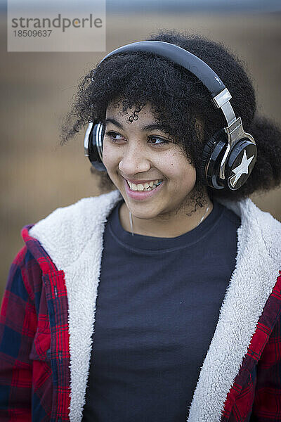biracial teen girl wearing headphones and smiling