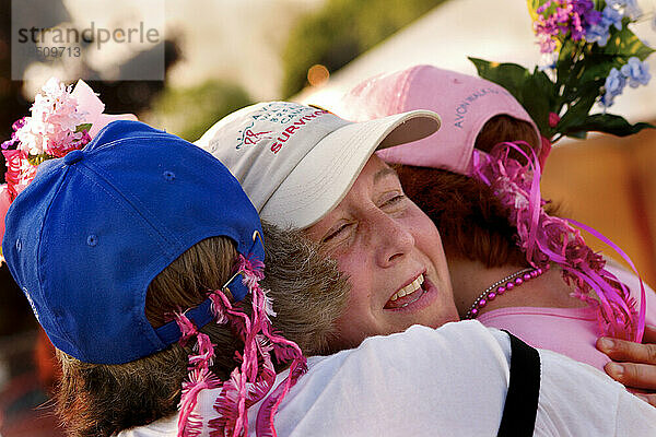 Eine Spaziergängerin und Brustkrebsüberlebende wird nach dem ersten Tag eines Brustkrebs-Spaziergangs von ihren Mitläufern umarmt.