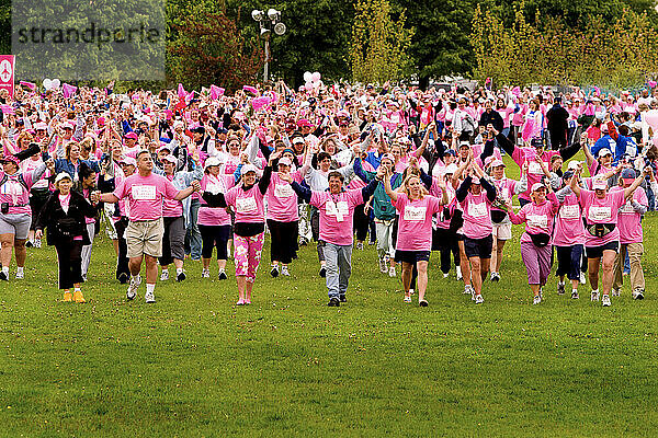 Walkers raise their arms in in solidarity at the end of a Boston breast cancer walk.