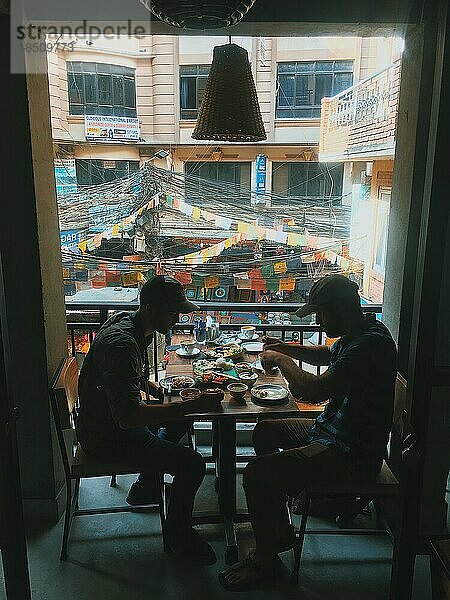 Zwei Männer beim Mittagessen mit Blick auf die Straßen der Stadt in Asien