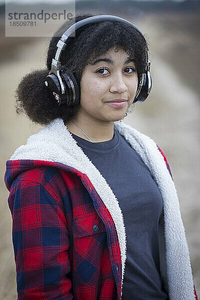 biraziales Teenager-Mädchen mit Kopfhörern und ernstem Gesichtsausdruck