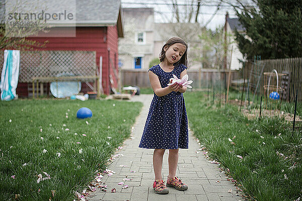 Ein kleines Kind hält zärtlich eine Magnolienblüte in den Händen