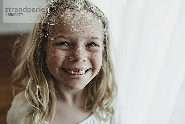 Porträt eines jungen sommersprossigen lächelnden Mädchens  dem ein Zahn fehlt