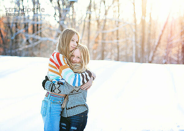 Zwei Teenager-Mädchen umarmen sich an einem Wintertag im Freien.