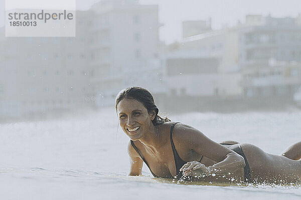 Eine Surferin lächelt beim Paddeln im Meer