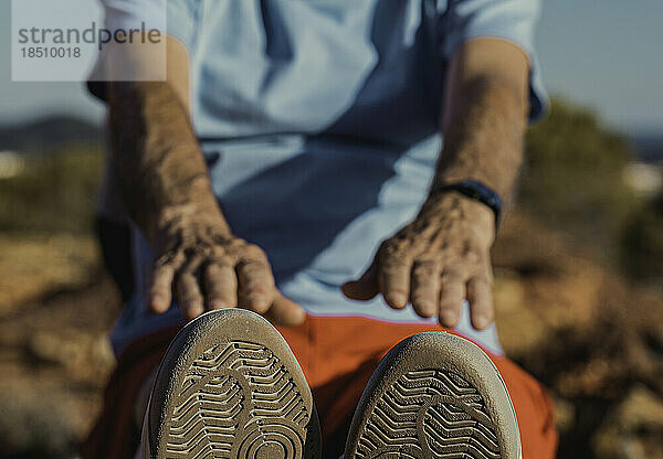 Älterer Mann macht nach dem Laufen einige Dehnübungen. Fokus auf Schuhe