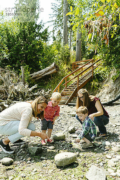 Seitenansicht einer Familie  die gemeinsam Gezeitentümpel an einem felsigen Strand erkundet