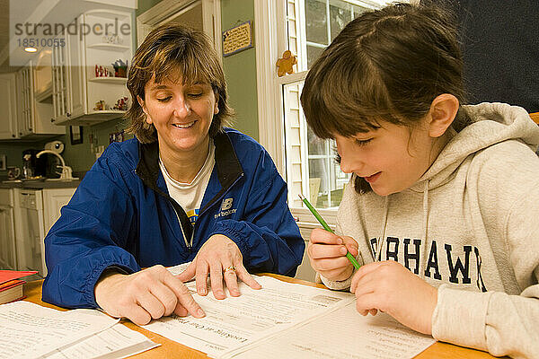 Eine Mutter hilft ihrer zehnjährigen Tochter bei den Hausaufgaben.