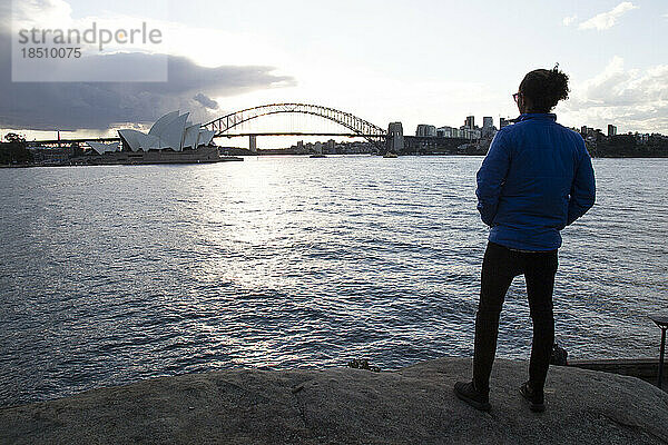 Ein Mann starrt bei Sonnenuntergang auf das Sydney Opera House