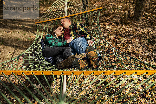 Paar umarmt sich entspannt in der Hängematte im Herbstlaub