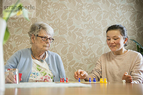 Mädchen spielt Brettspiel mit Seniorin im Pflegeheim