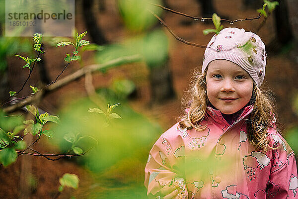 Süßes blondes Kind lächelt in die Kamera im Wald
