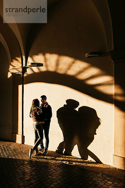 Mann und Frau umarmen sich in den Sonnenstrahlen mitten in der Altstadt von Prag