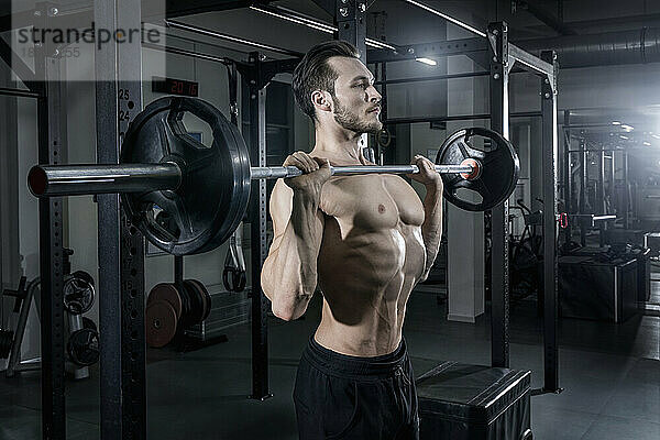 Nackter Oberkörper  muskulöser Mann  der im Fitnessstudio mit der Langhantel trainiert
