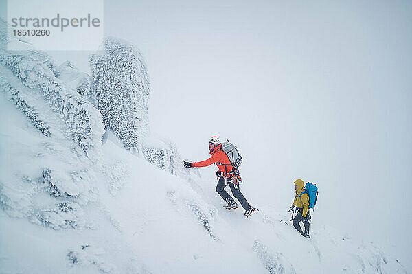 Eiskletterer erklimmen einen gefrorenen Alpenrücken auf einem Berg