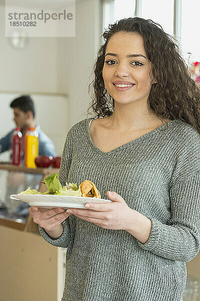 Universitätsstudentin mit ihrem Mittagessen auf dem Teller und lächelnder Schule  Bayern  Deutschland