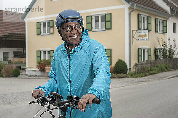 Glücklicher älterer Mann mit Fahrradhelm auf seinem Fahrrad  Bayern  Deutschland