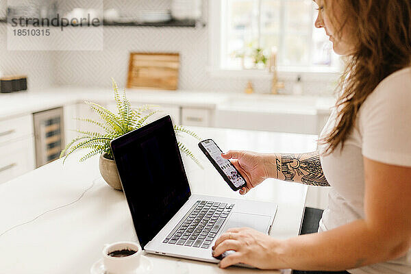 Side view of white adult woman working on computer with coffee