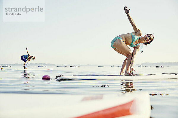 Zwei junge Frauen machen Yoga auf SUP-Boards